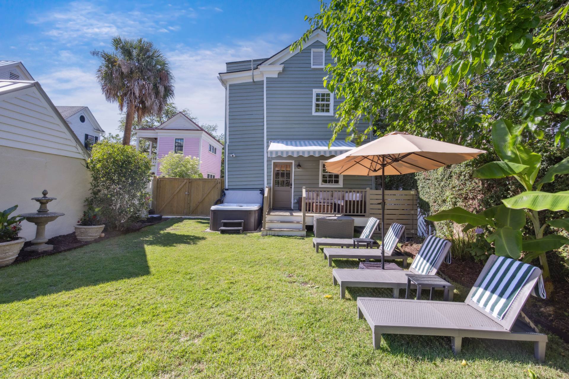 Suite A wellness yard with hot tub, loungers, and umbrella